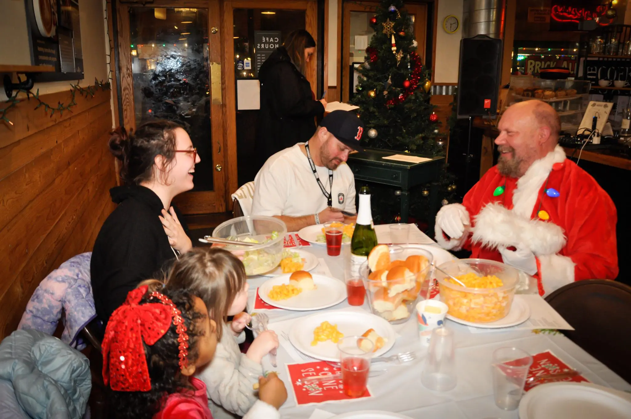 A young woman sits across from youth program staff, while they enjoy a holiday meal together.