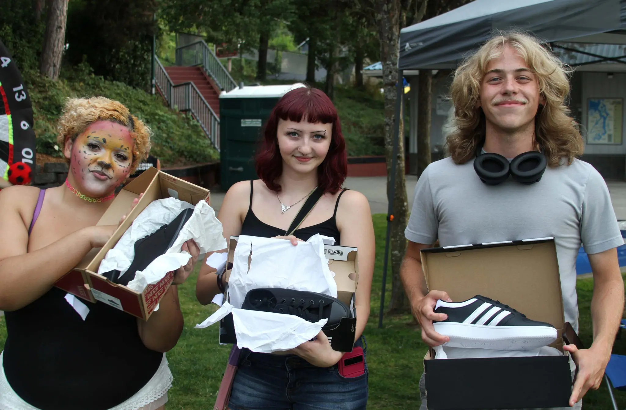B2B-2026-10 Three youth show off their new shoes at The Coffee Oasis back to school event. They hold the boxes of shoes in front of them.