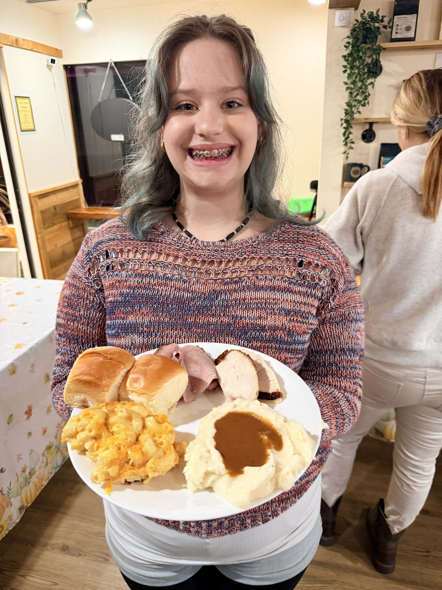 Thanksgiving-8 A smiling young woman holds a plate of Thanksgiving food in front of her.